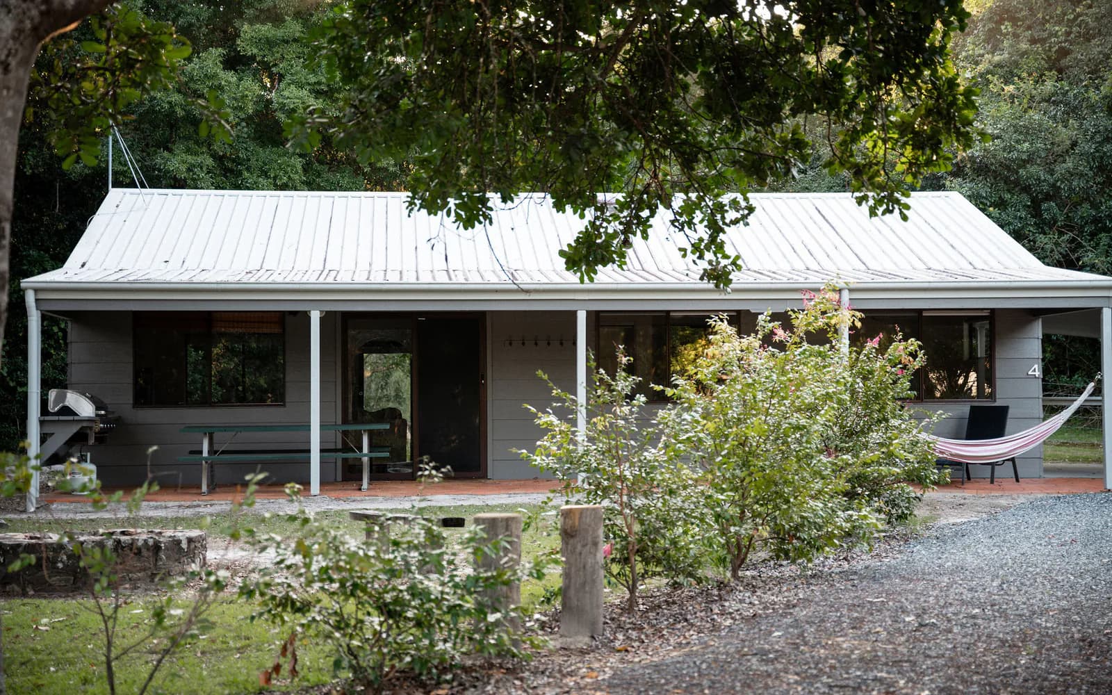 A cottage verandah and hammock behind the garden, late afternoon